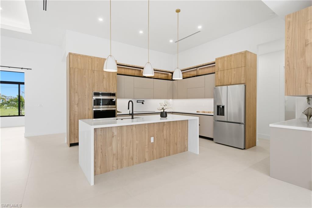 Under-cabinet LED lighting, pot filler, built-in wall oven & microwave, induction cooktop, hidden range hood, integrated cabinetry, designer pendant lighting, spacious pantry & premium stainless appliances