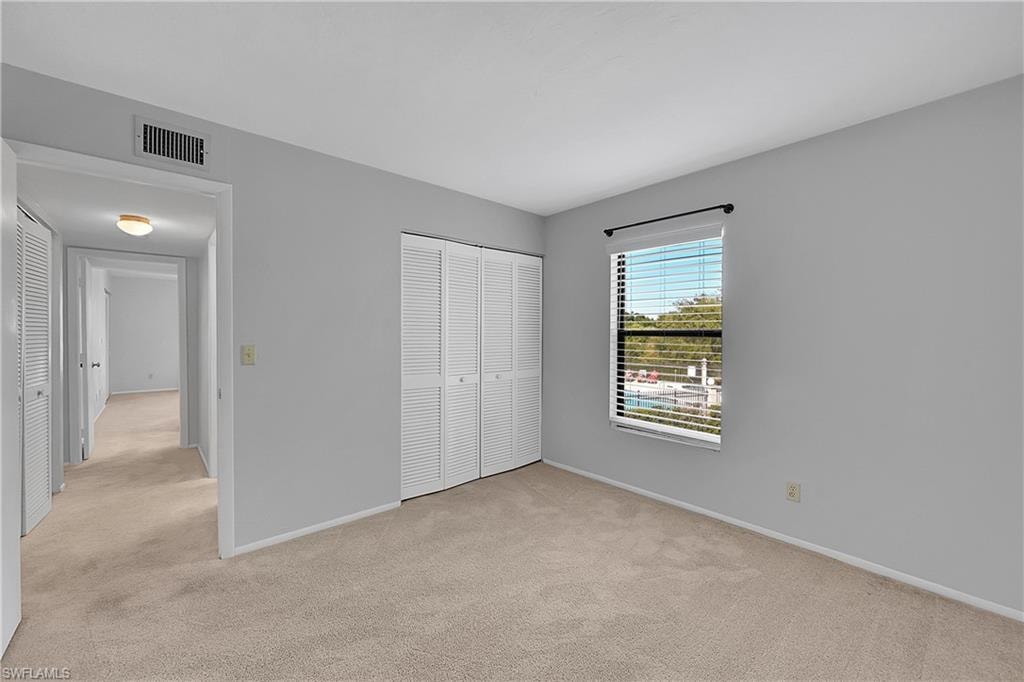 Unfurnished bedroom with light carpet and a closet