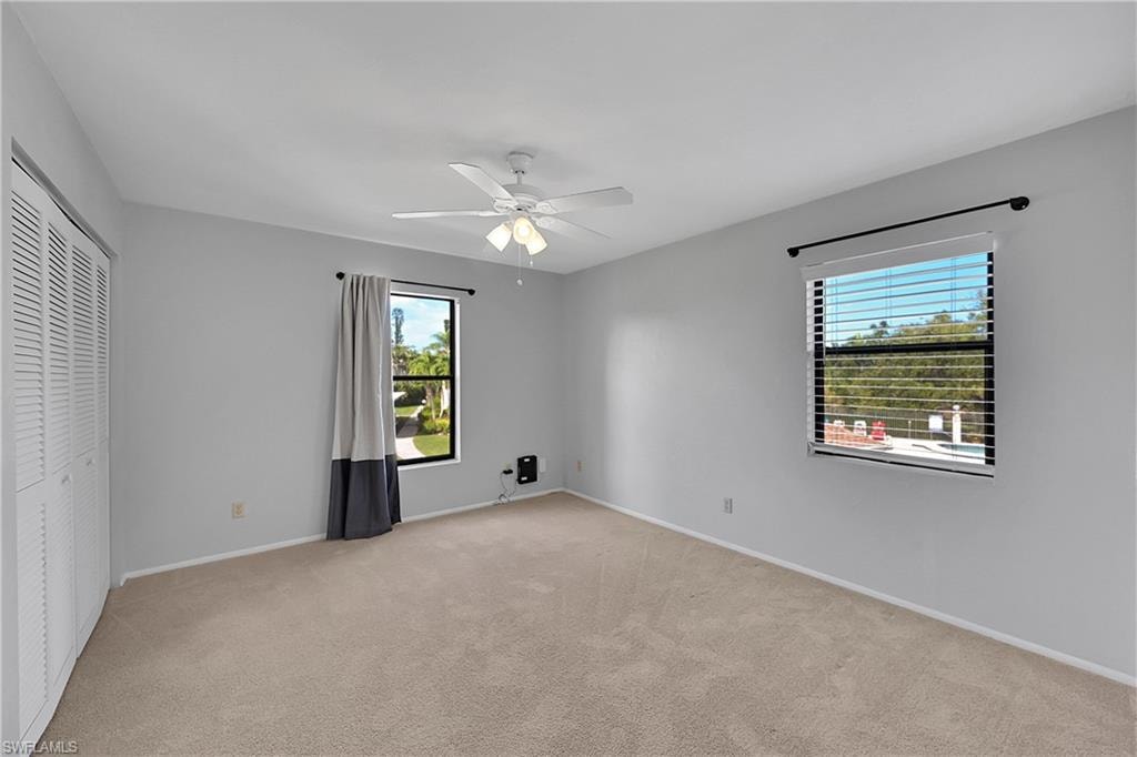 Unfurnished bedroom featuring light colored carpet, ceiling fan, and a closet