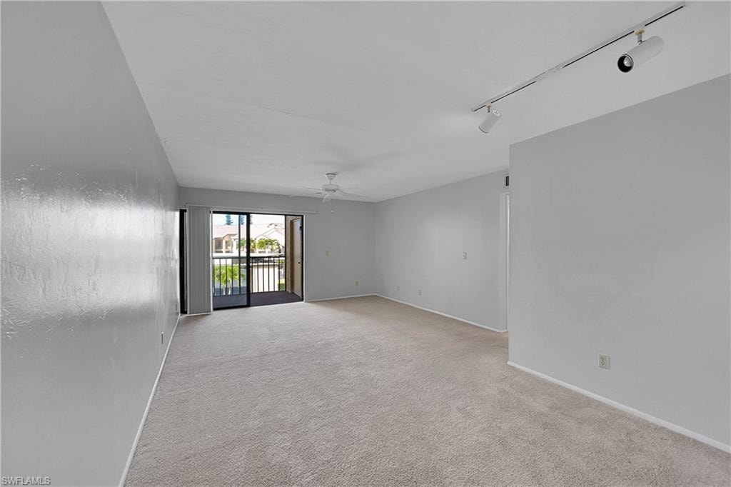 Unfurnished room with light colored carpet, rail lighting, and ceiling fan