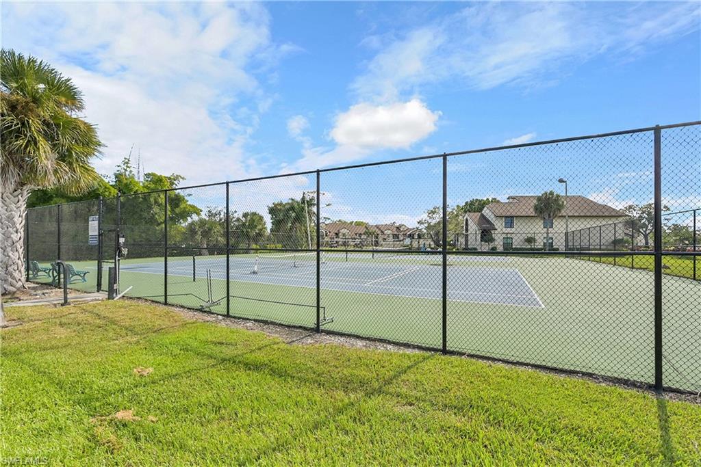View of tennis court with a residential view