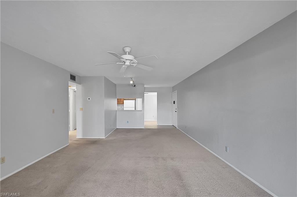 Unfurnished living room with light carpet and a ceiling fan
