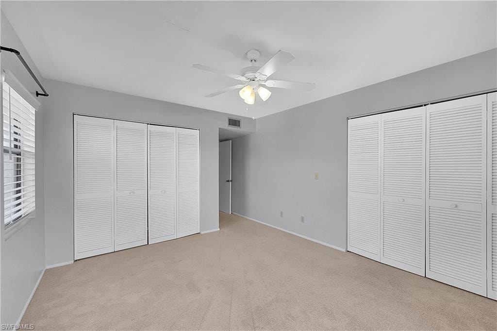 Unfurnished bedroom with multiple closets, light colored carpet, and ceiling fan