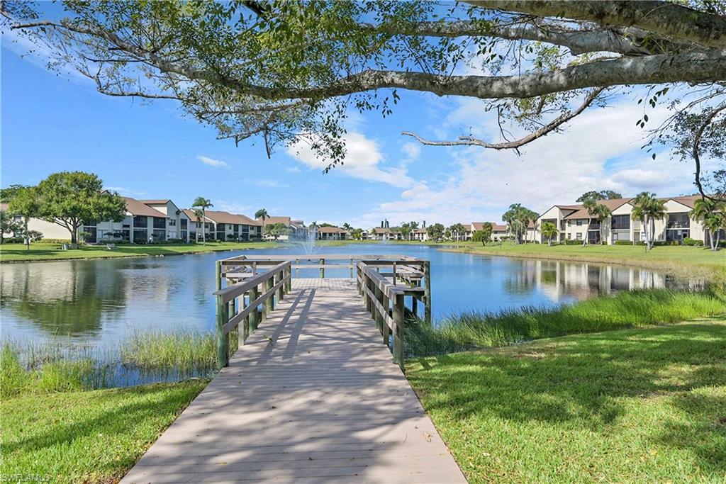 Dock area with a water view, a residential view, and a lawn