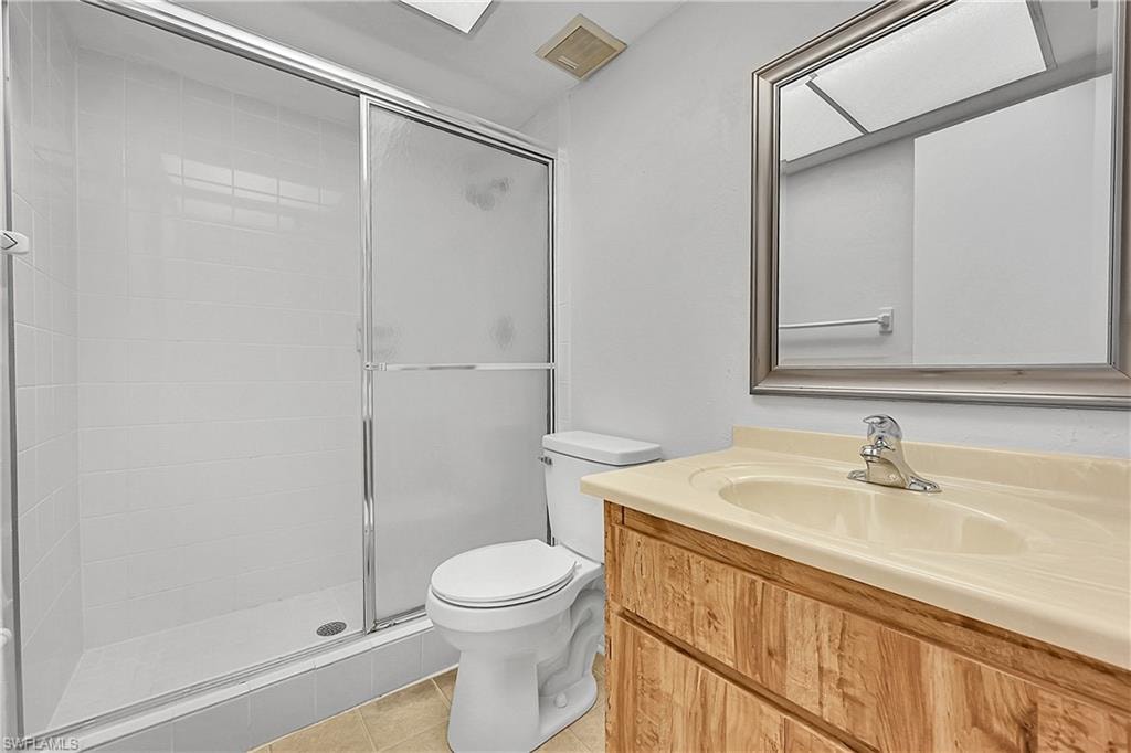 Full bath with light tile patterned floors, vanity, and a shower stall