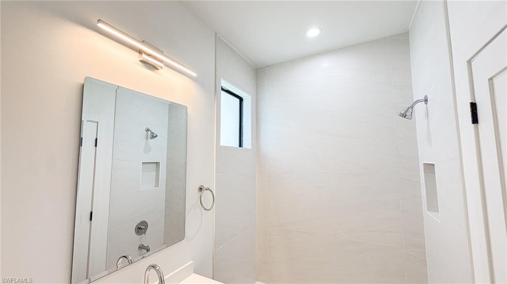 Contemporary bathroom featuring white walls, a rectangular mirror, and a linear vanity light fixture