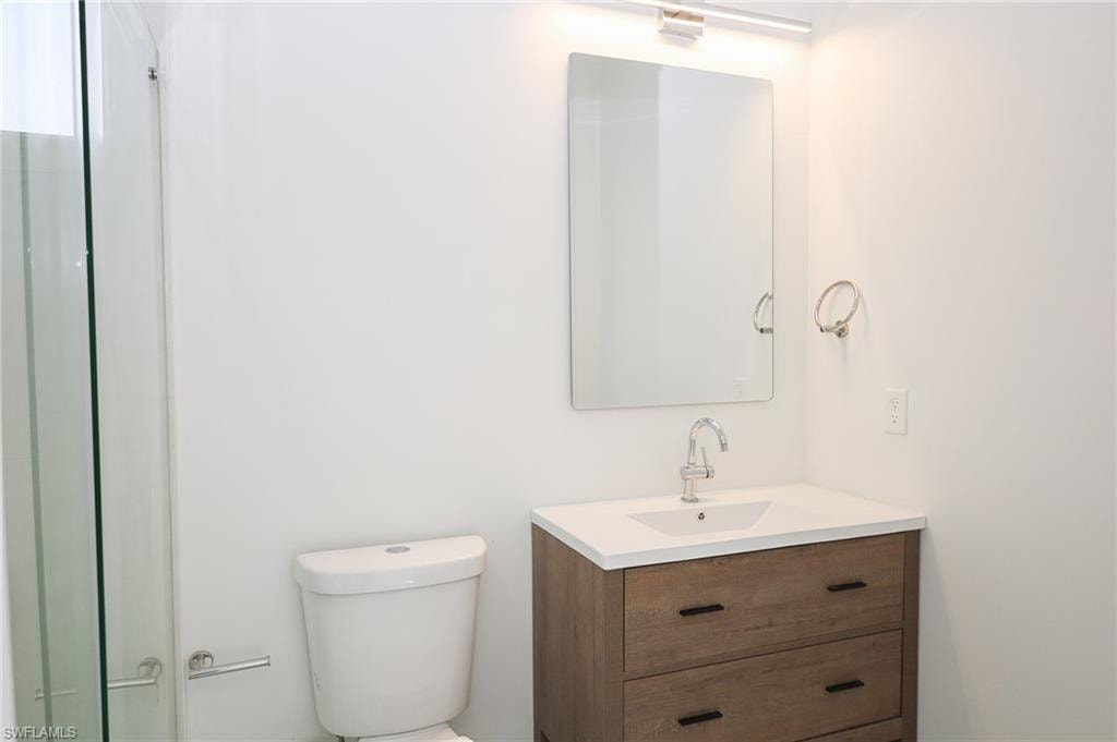 Bathroom featuring a wood-finish vanity with a white countertop and integrated sink, a rectangular mirror, and an overhead vanity light