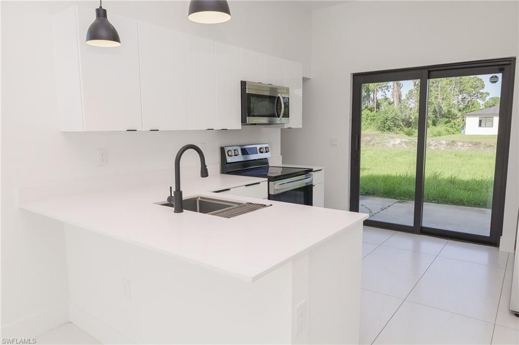 Modern kitchen featuring white cabinetry, light countertops, and stainless steel appliances