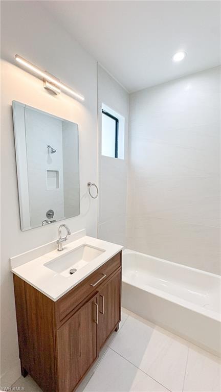 Bathroom featuring a white bathtub, wood-finish vanity with a single sink, integrated countertop, and chrome fixtures