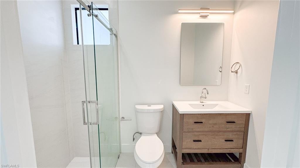 Modern bathroom featuring a wood-finish vanity with a white countertop and undermount sink, a sleek rectangular mirror, and an illuminated vanity light bar