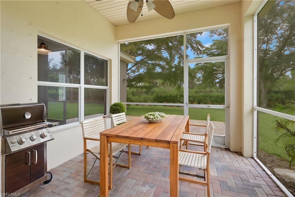 Virtually staged screened patio featuring a ceiling fan, a large window, and brick paver flooring