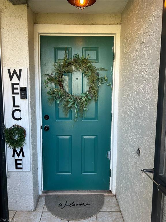 Entryway featuring a screened front door, arched portico with teal accent, and concrete pathway