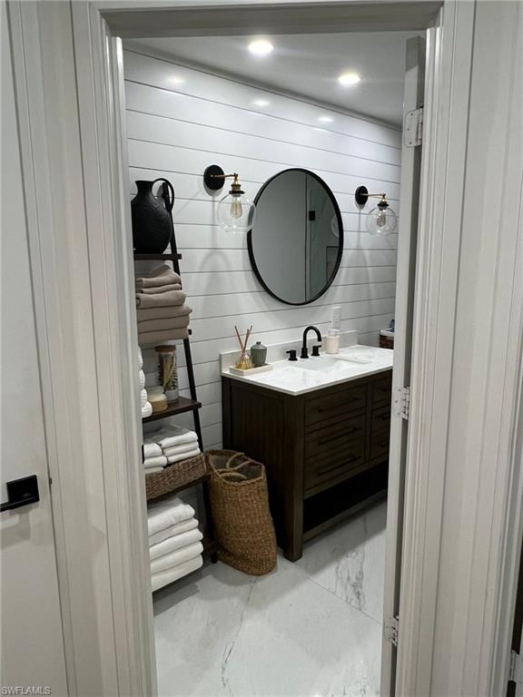 Bathroom featuring a dual-sink vanity with white countertop, dark wood-finish cabinetry, and matte black fixtures