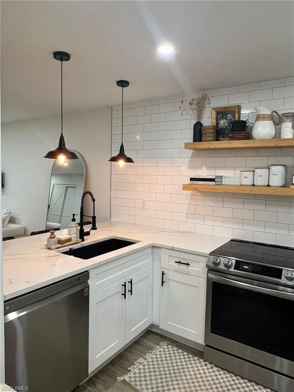 Modern kitchen featuring white shaker cabinetry with black hardware, white stone-finish countertops, and a subway tile backsplash