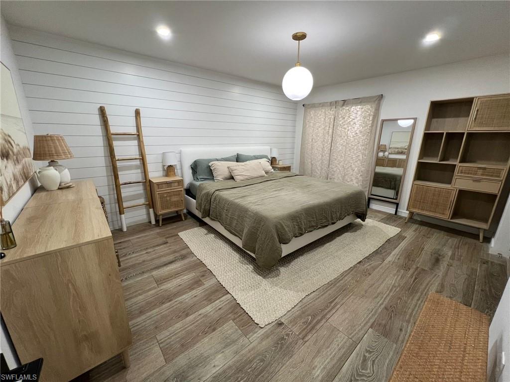 Bedroom featuring wood-finish flooring, a shiplap accent wall, and recessed ceiling lighting