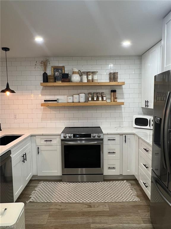 Kitchen featuring a stainless steel electric range, white shaker-style cabinetry with black hardware, and light-toned countertops