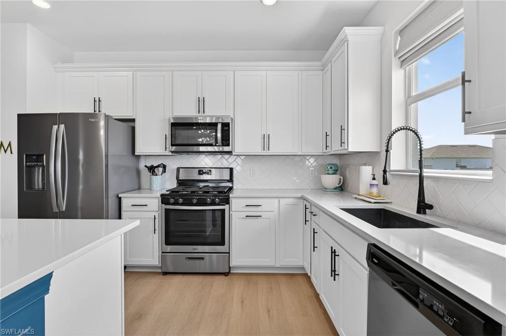 Modern kitchen featuring white shaker cabinetry and light-toned countertops