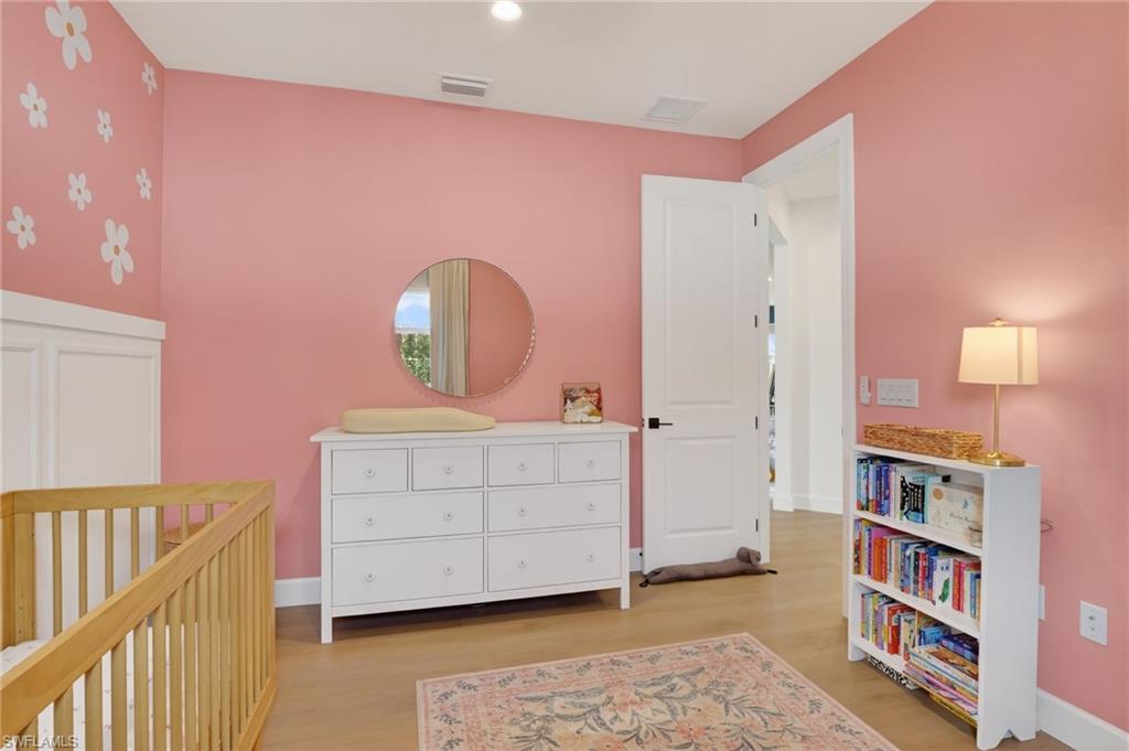Interior room featuring wood-finish flooring and a white paneled door with dark hardware
