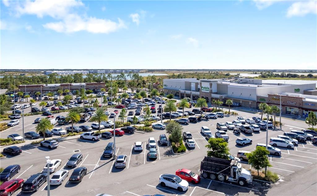 Expansive retail complex featuring multiple storefronts, a large paved parking area, and mature palm tree landscaping