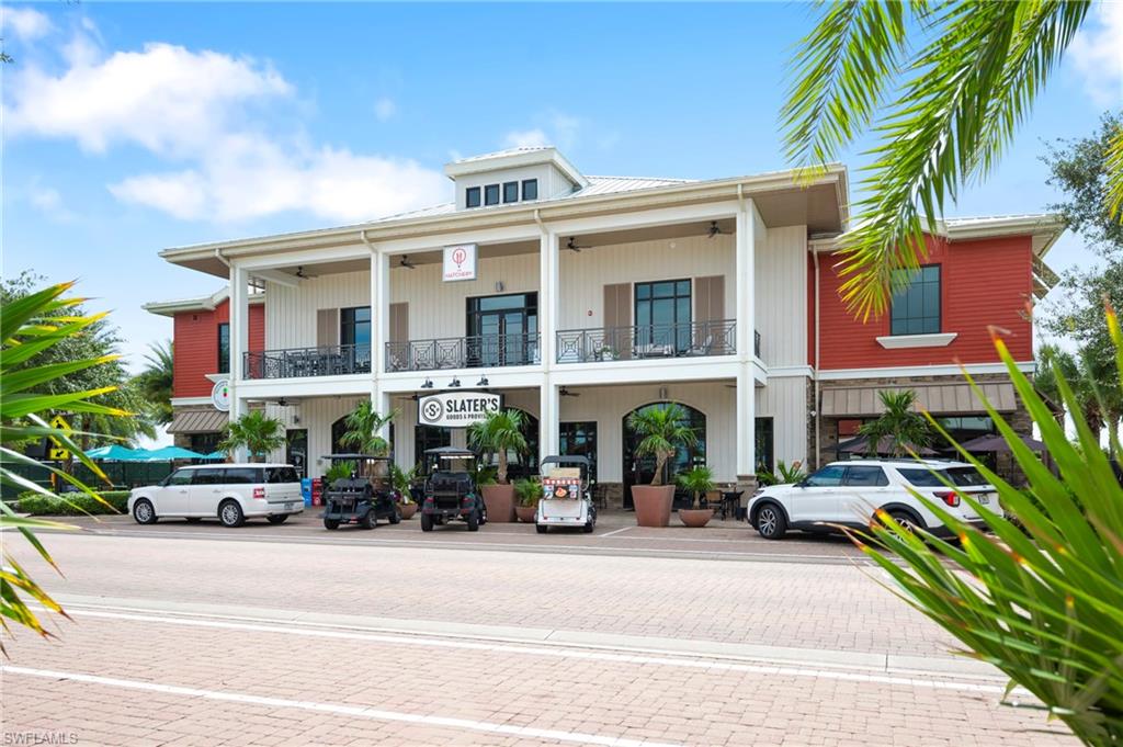 Two-story commercial building featuring red and white vertical siding, prominent balconies with black railings, and a ground-floor awning