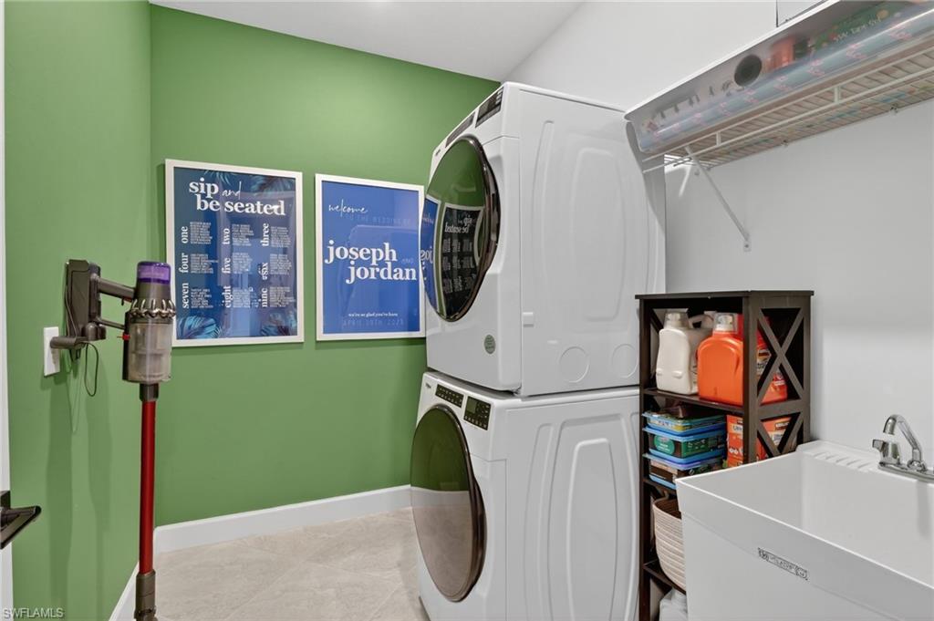 Laundry area featuring a utility sink, wall-mounted wire shelving, and light-toned flooring