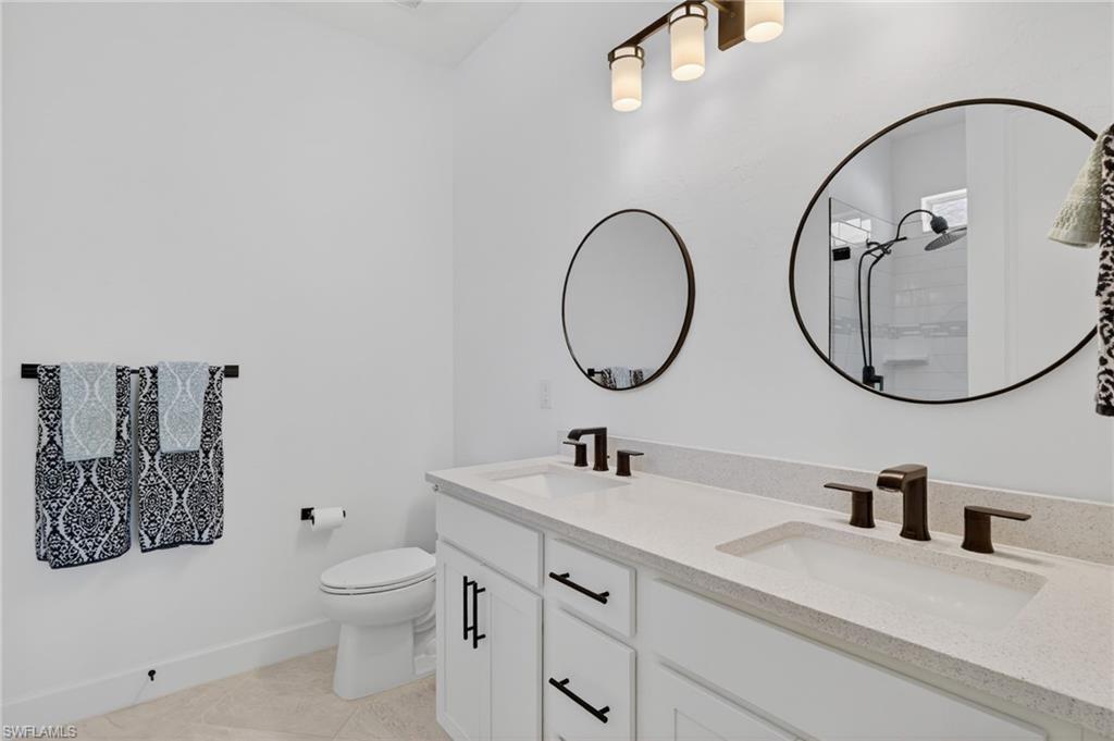 Dual vanity with white cabinetry and integrated sinks, complemented by dark bronze fixtures and hardware