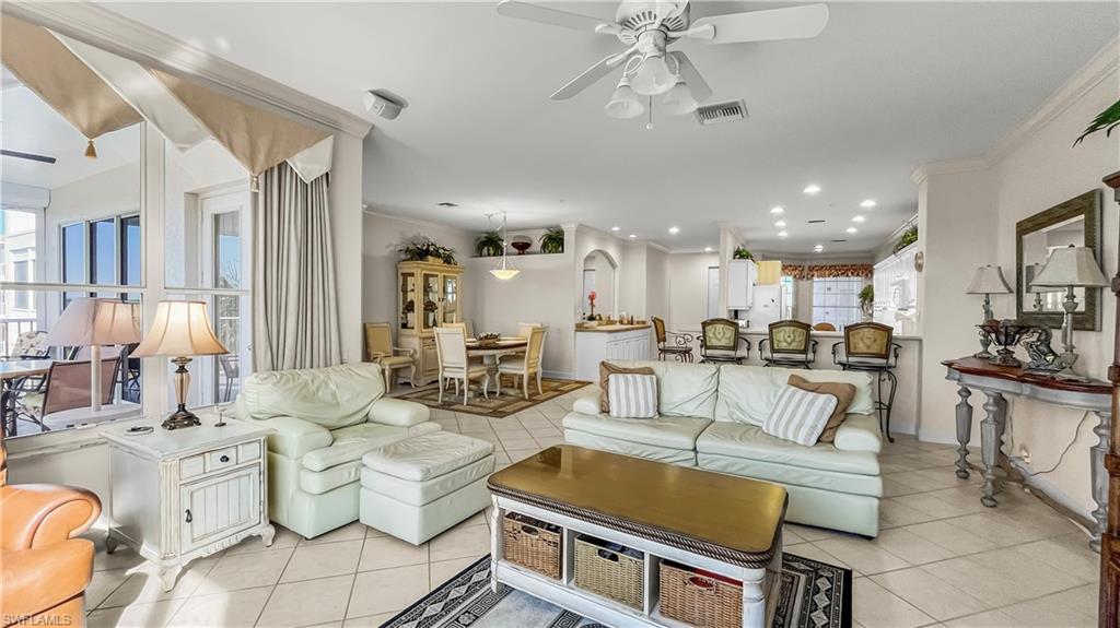 Tiled living room featuring plenty of natural light, ceiling fan, and crown molding
