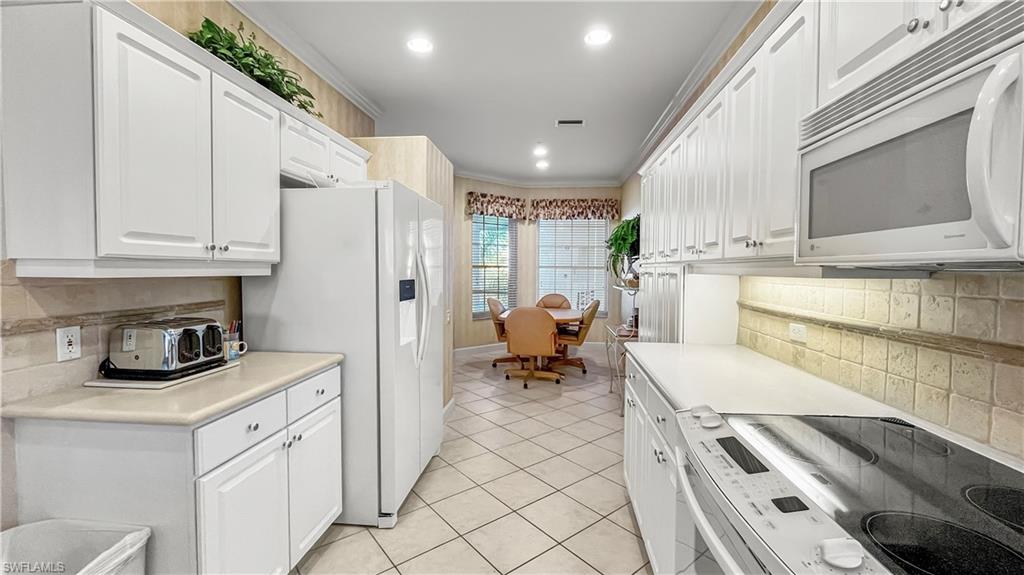 Kitchen featuring white cabinets, white appliances, and crown molding