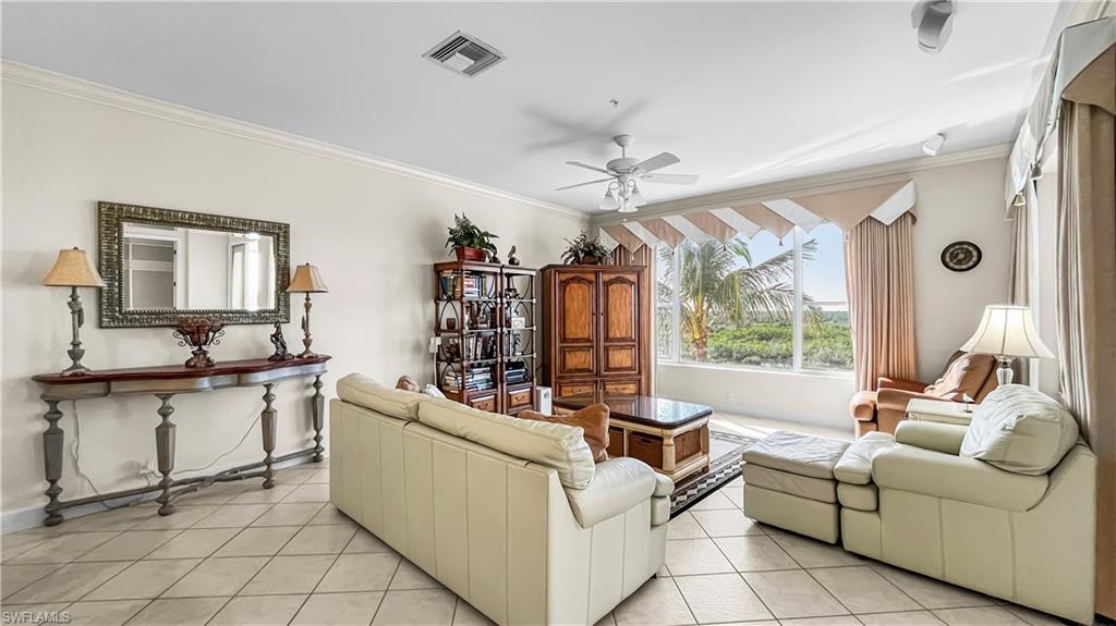 Living room featuring light tile patterned floors, ceiling fan, and crown molding