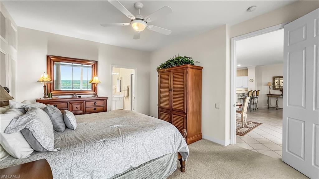 Carpeted bedroom with ceiling fan and ensuite bathroom