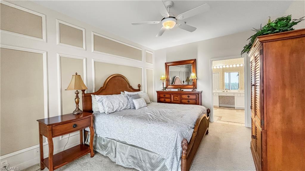 Carpeted bedroom featuring ensuite bath and ceiling fan