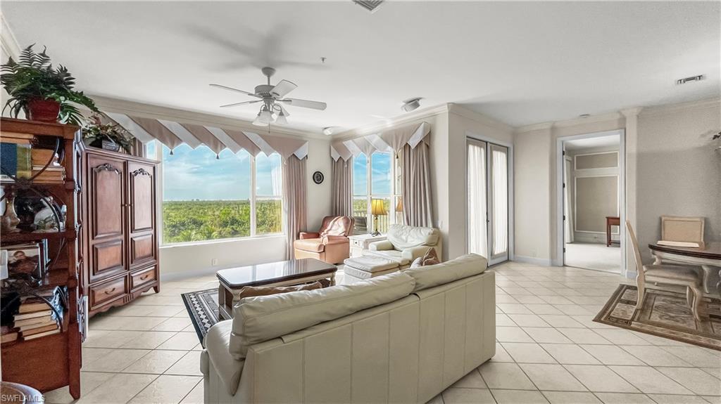 Living room featuring ceiling fan, crown molding, and light tile patterned flooring