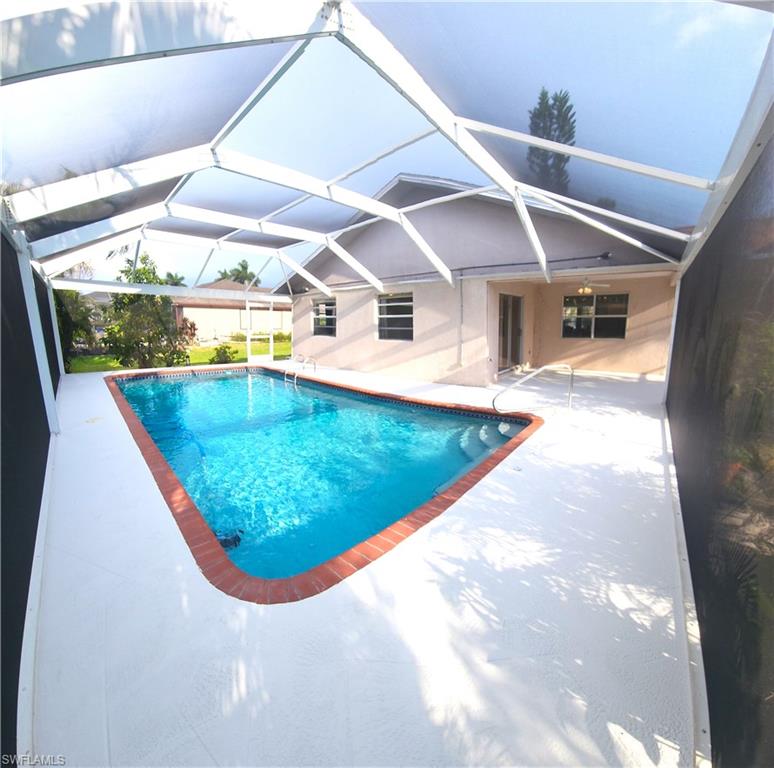Screened-in pool area featuring a rectangular pool with integrated steps, a brick coping, and a surrounding white deck