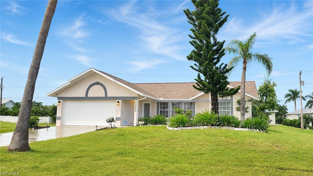 Contemporary single-story residence featuring a two-car garage, mature landscaping, and an inviting front yard with a palm tree