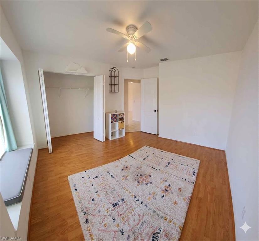 BDRM 2 Bright room featuring wood-finish flooring, a ceiling fan with integrated lighting, and a window with a built-in window seat