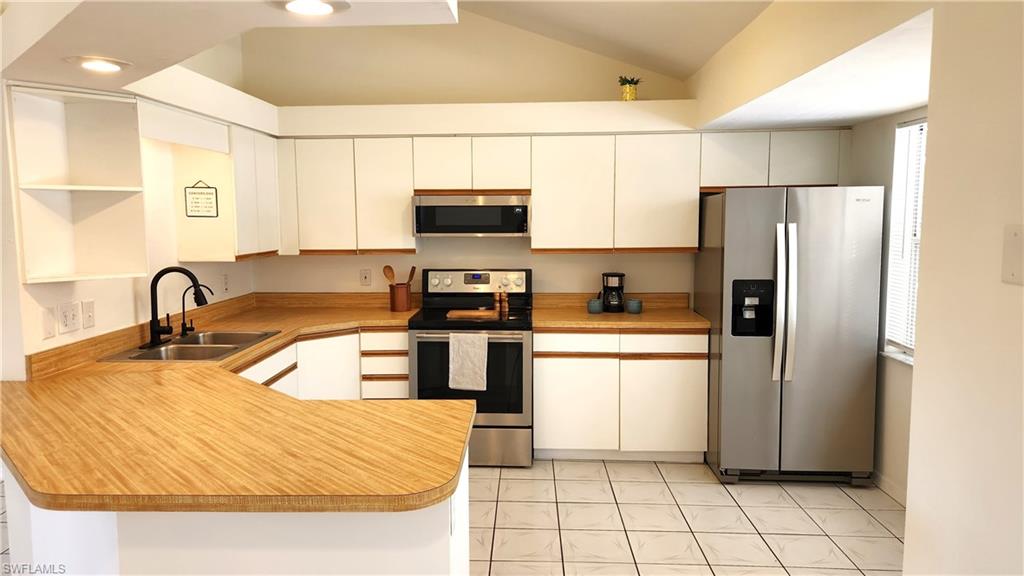 Kitchen featuring wood-finish countertops, white cabinetry, and stainless steel appliances