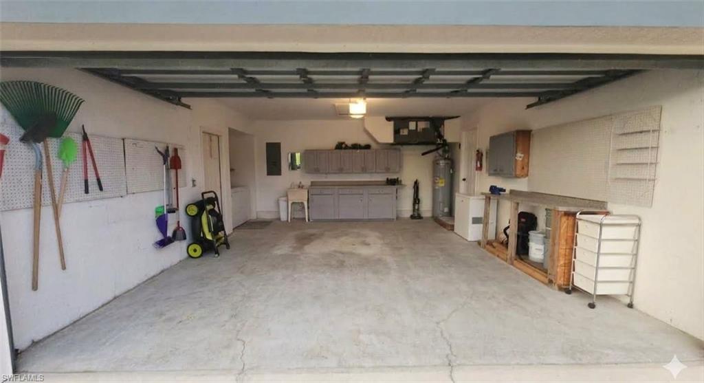 Spacious garage featuring a concrete floor, built-in cabinetry, a utility sink, and ample wall-mounted storage solutions
