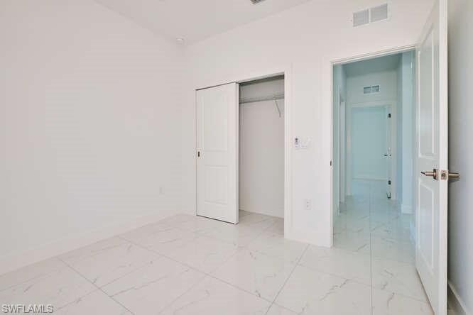 Unfurnished bedroom featuring light marble finish floors and a closet