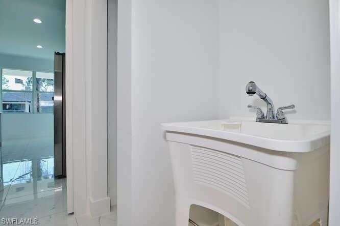 Bathroom featuring vanity, light marble finish flooring, and recessed lighting