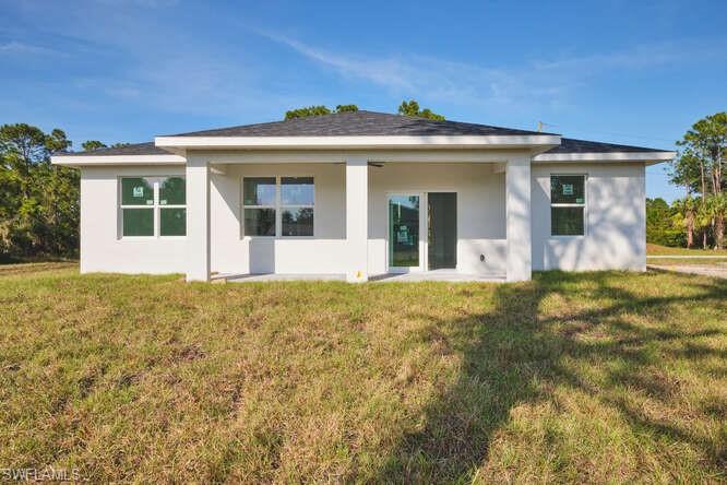 Rear view of house featuring stucco siding, a yard, and a patio area