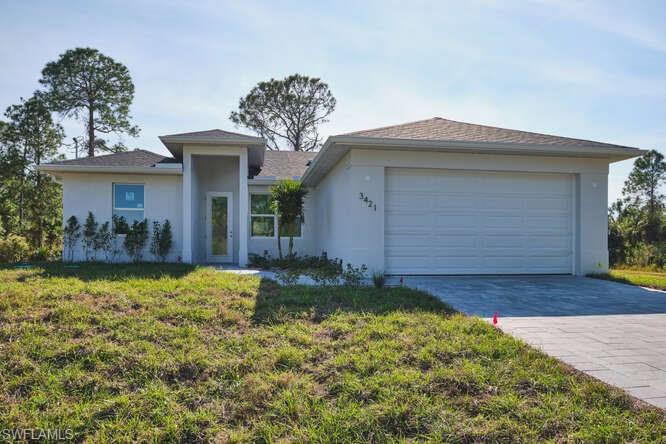 View of front of home with stucco siding, a front lawn, decorative driveway, and an attached garage