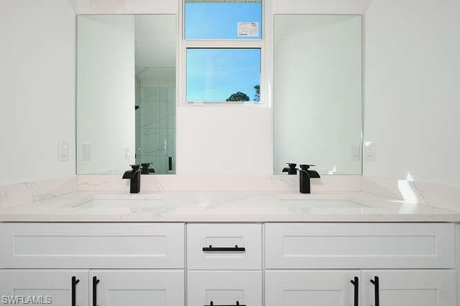 Full bathroom with double vanity and a marble finish shower