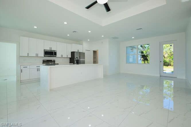 Kitchen with open floor plan, white cabinetry, an island with sink, light countertops, and stainless steel appliances