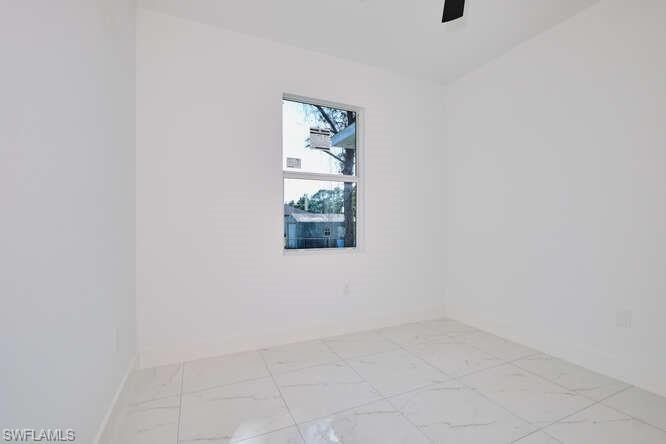 Spare room with light marble finish flooring and baseboards