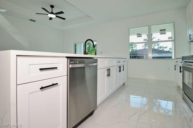 Kitchen featuring white cabinetry, stainless steel appliances, light countertops, and healthy amount of natural light