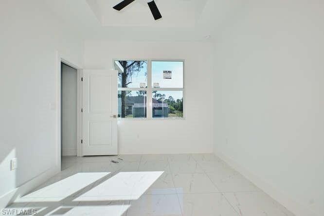Unfurnished room featuring light marble finish floors and baseboards