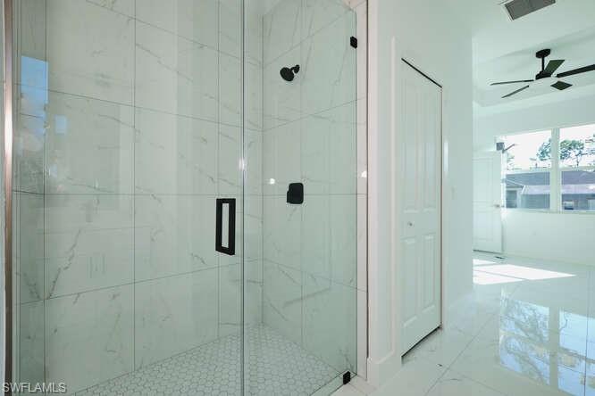 Bathroom with a marble finish shower and ceiling fan