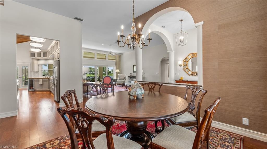 Formal dining area featuring rich wood-finish flooring, a decorative chandelier, and an arched entryway