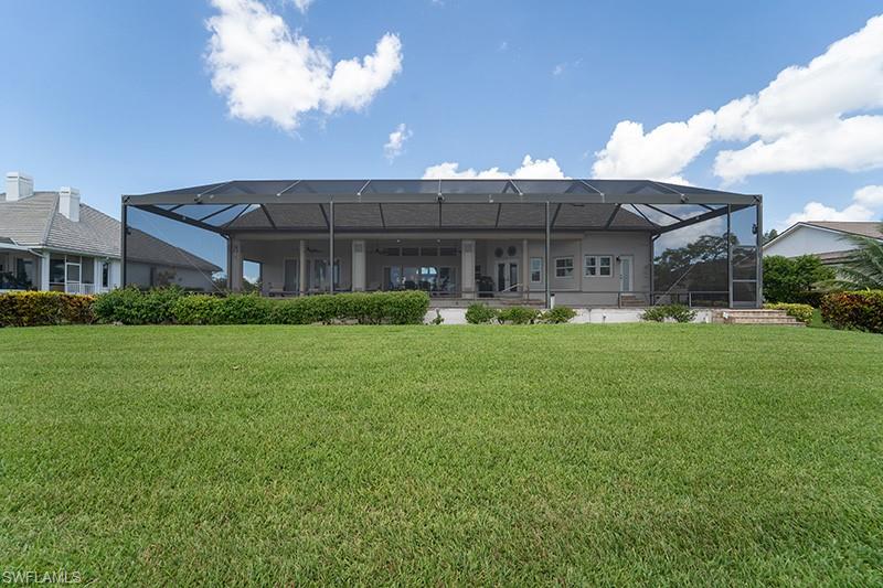 Expansive rear exterior featuring a screened-in lanai, covered patio space, and a manicured lawn