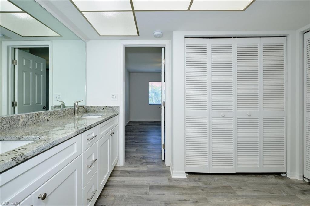 Bathroom featuring a double vanity with stone countertop, white shaker-style cabinetry, and integrated sinks